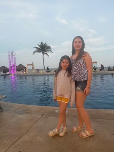My daughters looking at the camera, smiling, next to one of the main pools. 